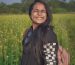 happy woman wearing black sweater standing on a flower field