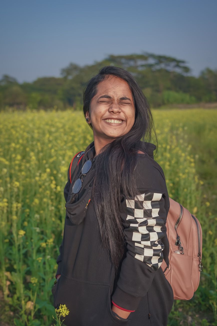 happy woman wearing black sweater standing on a flower field